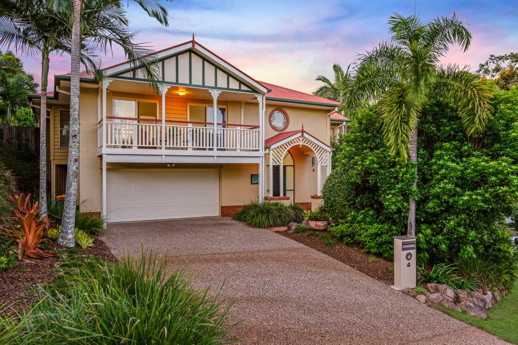 The front driveway leading up to a double storey home surrounded by palms