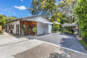 A 1 storey home with a large driveway leading to carport