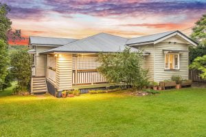 a single storey queenslander home with the sunset in the back ground