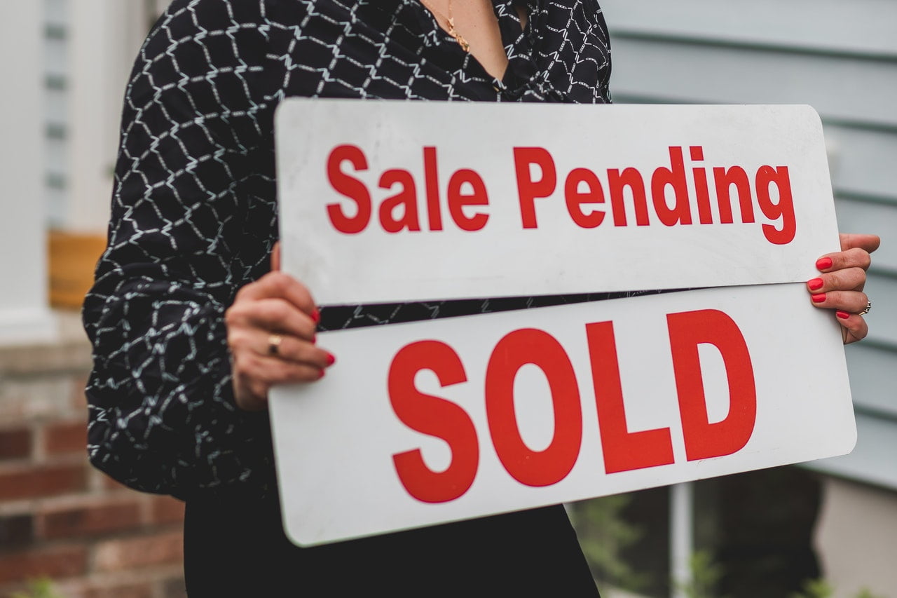 sale pending and sold signs held by a person