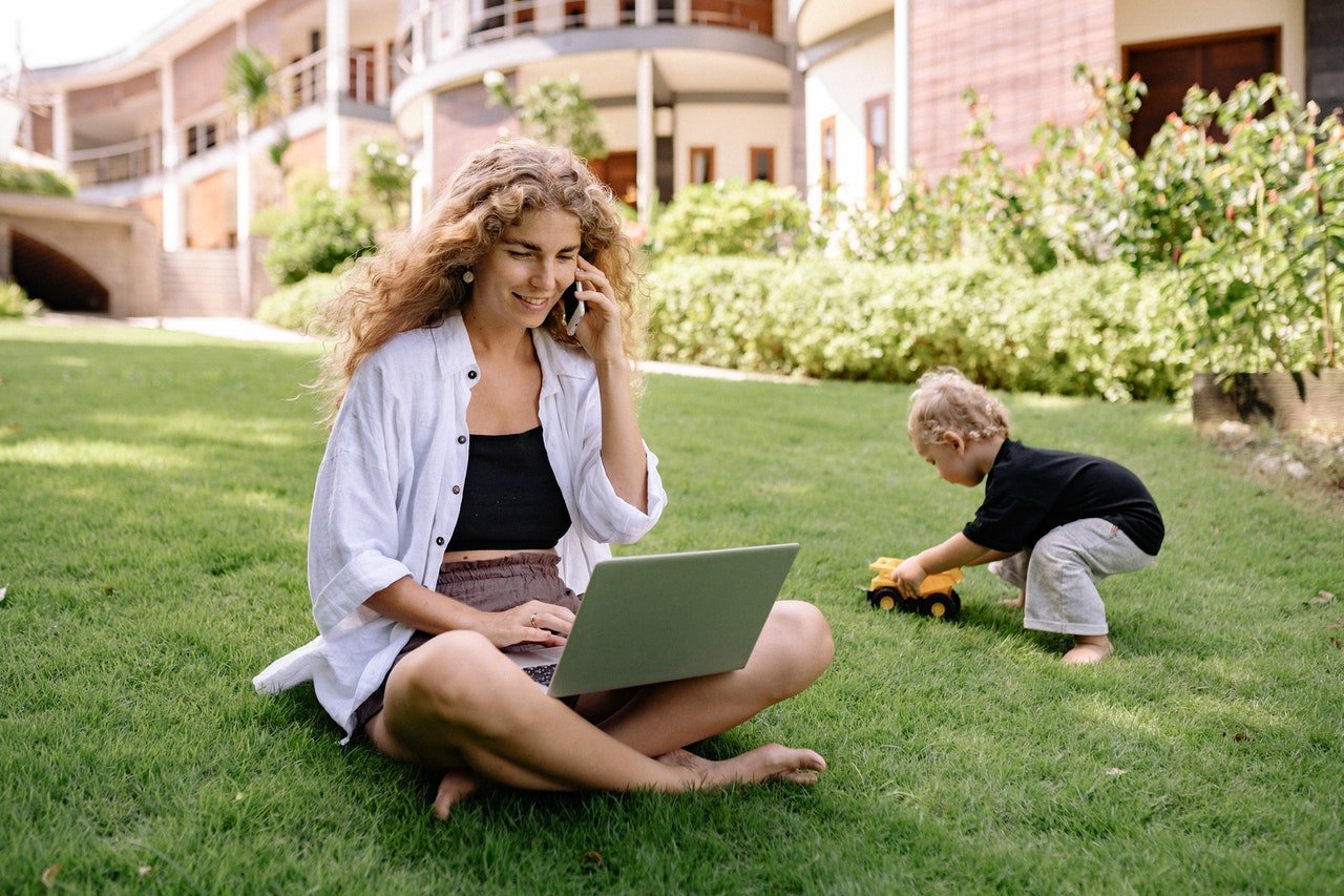 a woman talking on the phone while sitting in the grass