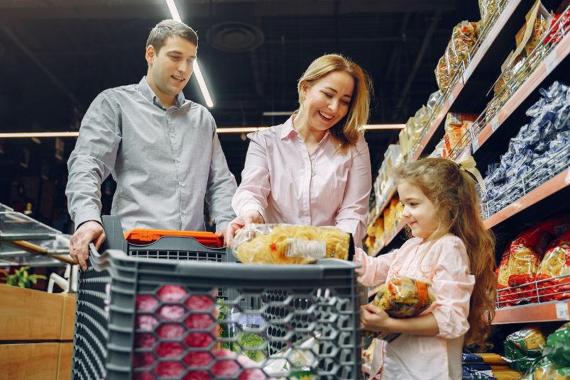 Dad mom and young girl putting groceries into cart
