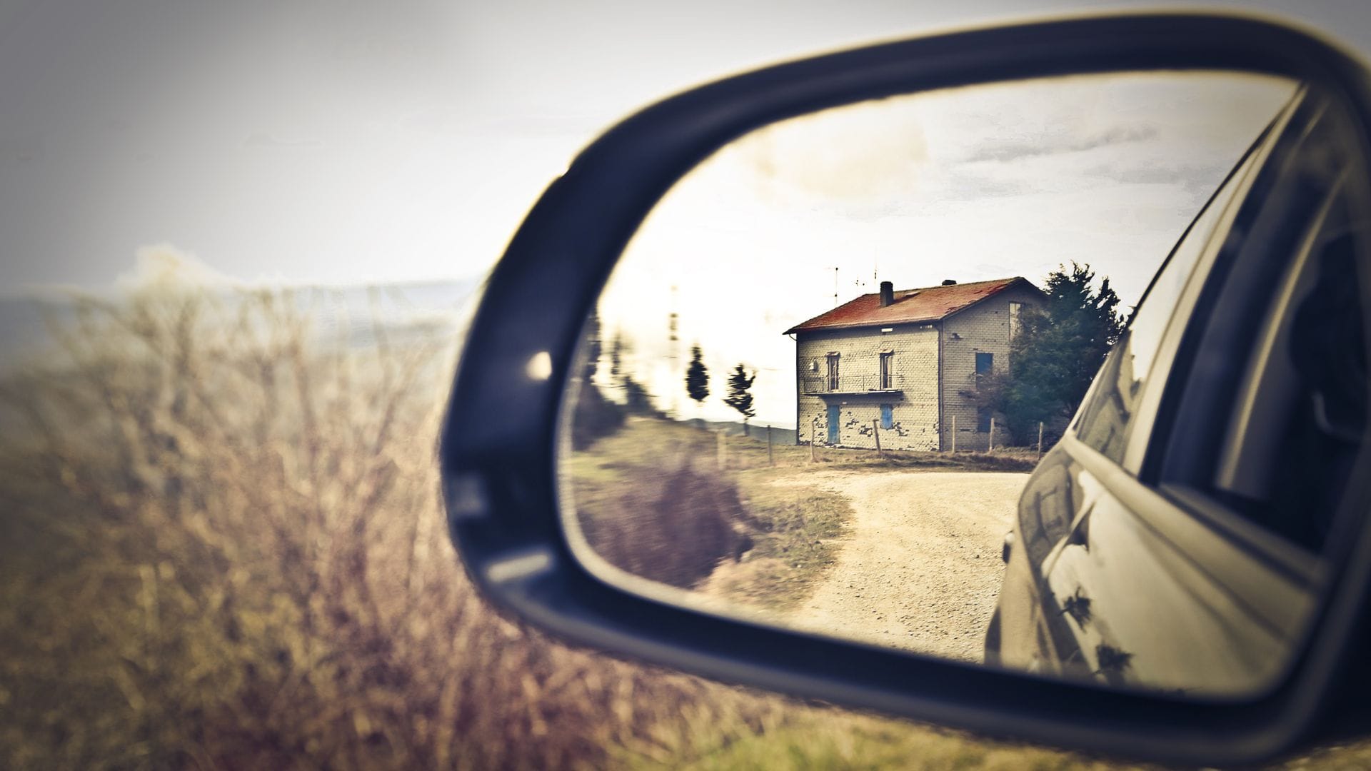 old run down house in rear vision mirror